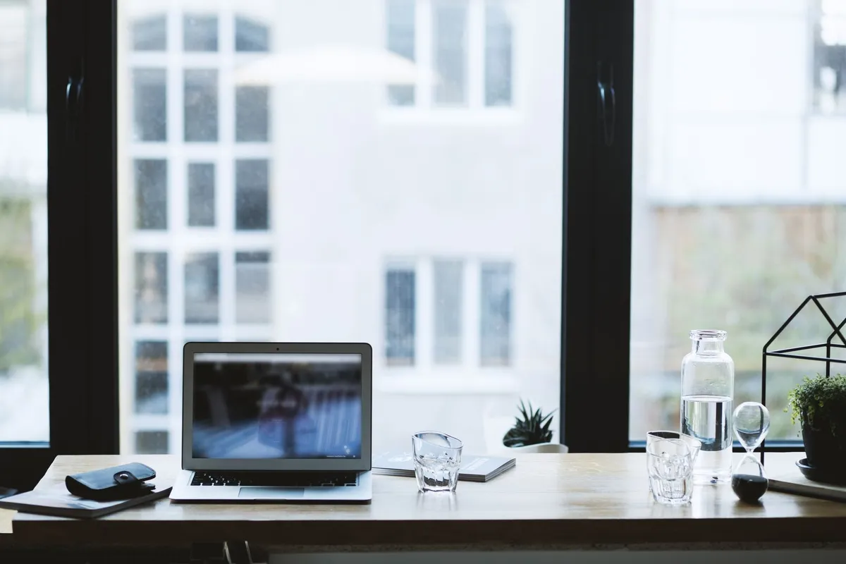 A modern office desk with a laptop and a glass of water, symbolizing the professionalism of bookkeeping services.